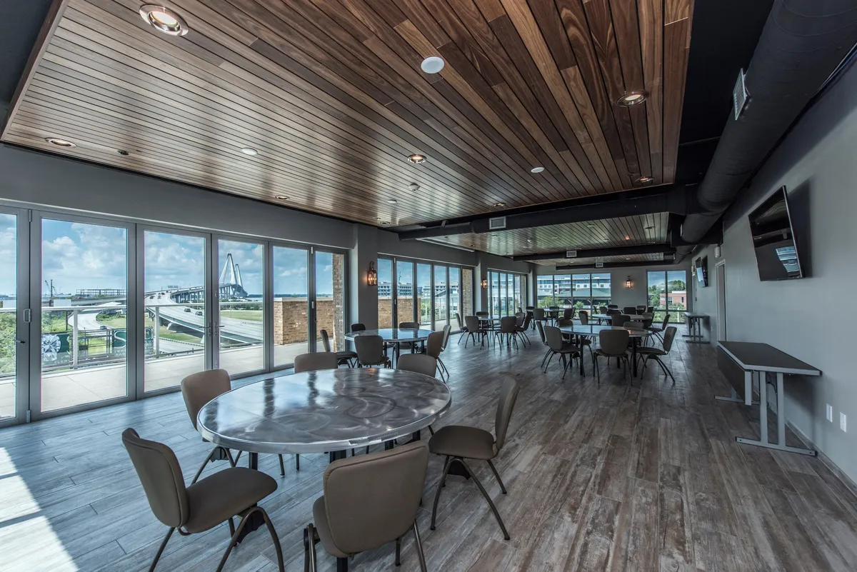 This interior image captures a bright, contemporary space featuring large windows that offer expansive views of the surrounding landscape. Modern circular tables and a wooden ceiling create a warm, communal environment suited for family gatherings or casual relaxation after a day of outdoor adventures.