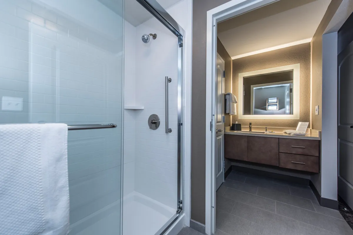 A sleek, modern bathroom featuring a glass shower enclosure, a stylish vanity with a large mirror, and contemporary fixtures. The space is well-lit and exudes cleanliness and tranquility.