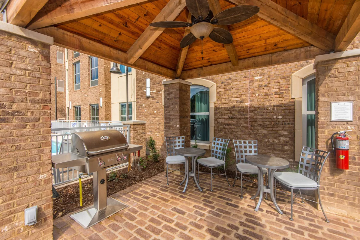This image shows an inviting exterior area equipped with a grill, outdoor seating, and a ceiling fan. The scene suggests a place where guests can barbecue, socialize, and relax together in the fresh air, underscoring the outdoor lifestyle promoted in the section.